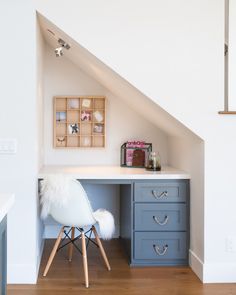 an attic bedroom with white walls and blue drawers