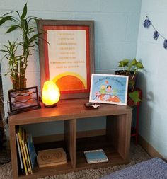 a wooden table topped with books and a lit candle next to a framed cartoon character