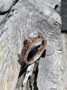 a ring sitting on top of a piece of wood with a diamond in the center