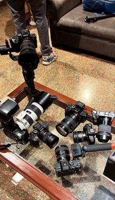 a table topped with lots of different types of cameras and equipment on top of it