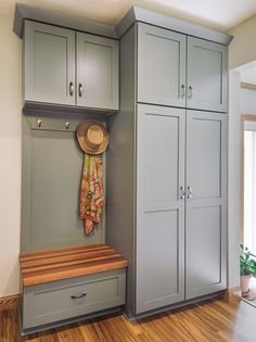 a room with gray cabinets and a wooden bench in the corner, next to a potted plant