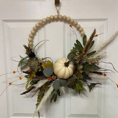 a wreath decorated with leaves and pumpkins hangs on the front door