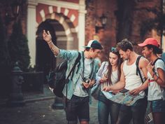 a group of young people standing around each other looking at a map and pointing to it