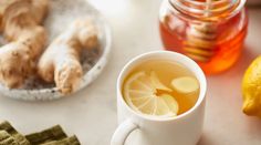 a cup of tea with lemon and ginger on the side