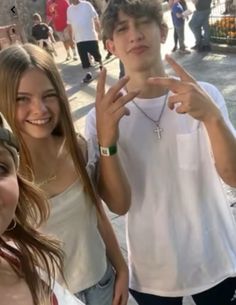 three young people standing next to each other in front of a crowd with one holding up the peace sign