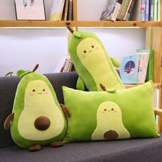 two green stuffed animals sitting on top of a gray couch next to bookshelves