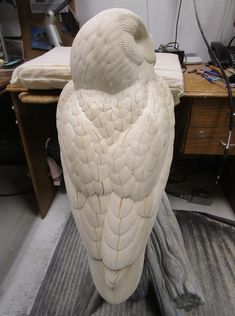 a white bird statue sitting on top of a wooden table next to a computer desk