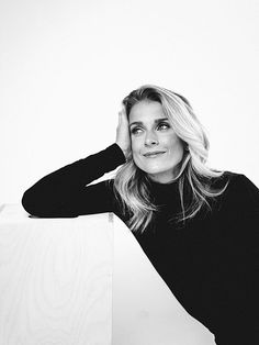 a black and white photo of a woman leaning against a wall with her hand on her head