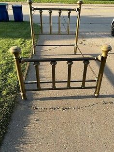 an old metal bed frame sitting in the middle of a sidewalk next to a car