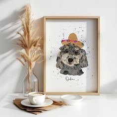 a watercolor painting of a dog with a hat on it's head next to a cup and saucer