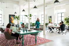 a group of people sitting at desks in an office with plants on the walls