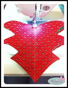 a red piece of fabric being sewn with a sewing machine in front of it