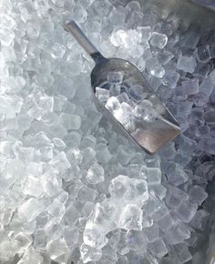 a scoop full of ice sitting on top of a metal pan filled with ice cubes