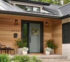 the front door of a house with potted plants and two chairs on the porch