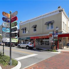 a street corner with cars parked on the side and several signs in front of it