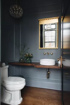 a white toilet sitting next to a sink in a bathroom under a golden framed mirror