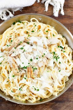 a bowl filled with chicken alfredo and parmesan cheese on top of a wooden table