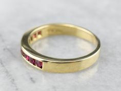 This is such an easy ring to wear! It sits low to the hand, and the sparkling ruby gemstones are set flush to the metal - there are no prongs to snag on this band! Crafted of 18 karat yellow gold, the flat sides will sit snug against an engagement ring, and stack with other bands with no gaps. Metal: 18K Yellow Gold Gem: 9 Rubies totaling .45 Carats Width of Band: 3.7 mm Height off Finger: 2.5 mm Ring Size: 8 Marks: "2063 21 SBI 18K" Stamped on the inside band Ruby Eternity Band With Prong Setting For Formal Occasions, Formal Ruby Eternity Band With Prong Setting, Classic Ruby Eternity Band For Formal Occasions, Gold Ruby Eternity Band For Anniversary, Yellow Gold Ruby Round Cut Eternity Band, Gold Ruby Ring With Baguette Cut And Prong Setting, Gold Ruby Eternity Band With Prong Setting, Gold Ruby Ring With Tension Setting For Formal Occasions, Channel Set Ruby Anniversary Rings