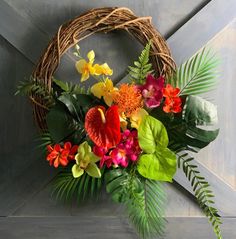 an arrangement of flowers in a wicker basket on a wall with palm leaves and foliage