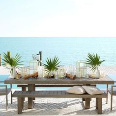 a wooden table sitting on top of a sandy beach next to the ocean with palm trees