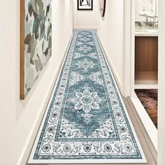 a blue rug is on the floor next to a white wall and framed pictures in a hallway