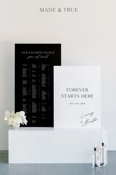 a couple of white flowers sitting on top of a table next to a black and white sign