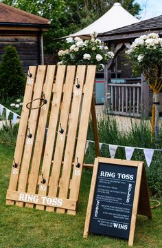 two wooden boards sitting in the grass next to a sign that says ring tosses