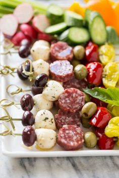 several skewered meats and vegetables on a white plate