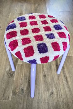 a stool made out of knitted material with purple and red squares on the top