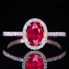 an oval shaped ruby and diamond ring with white diamonds on the sides, set in 18k gold