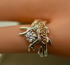 a close up of a person's hand wearing two rings with flowers on them