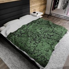 a bed with a green and black comforter on top of it in a bedroom