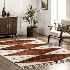 a living room area with a rug, chair and potted plant on the floor