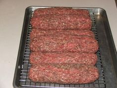 four hamburger patties sitting on top of a metal tray