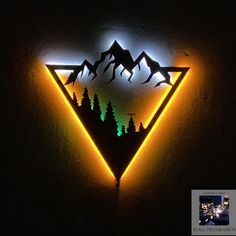 a neon sign with mountains and trees on it in the shape of a triangle is lit up against a dark wall