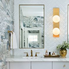 a bathroom vanity with two mirrors and lights on the wall next to it is decorated in blue and gold