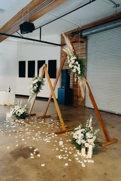 an arrangement of flowers and greenery is arranged on the floor in front of two wooden stands