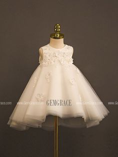 a white dress with flowers on it is sitting on a mannequin headdress