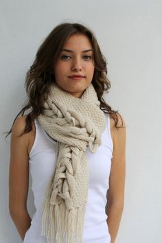 a woman wearing a white tank top and a beige knitted scarf with fringes