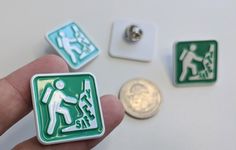 a hand holding a green and white sign next to a coin