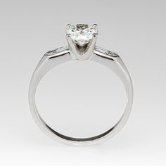 This gorgeous circa 1950s engagement ring is centered with a round transitional cut diamond weighing 1.01 carats and set into a four-prong head. The shoulders of the ring are each accented with a baguette cut diamond and a round single cut diamond. The ring measures 6.4mm at the top and rises 5.9mm above the finger. The ring is currently a size 7.25 and we offer complimentary resizing to fit. Gia Certified Classic White Gold Diamond Ring, Classic Round Gia Certified Diamond Ring, Gia Certified Timeless Princess Cut Diamond Ring, Gia Certified Princess Cut Diamond Ring, Classic Gia Certified Lab-grown Diamond Ring, Gia Certified Classic Lab-grown Diamond Wedding Ring, Gia Certified Classic Cut Diamond Anniversary Ring, Classic Gia Certified Round Band Ring, Gia Certified Classic Cut Diamond Ring For Anniversary