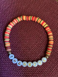 a colorful beaded bracelet with words on it sitting on top of a purple surface