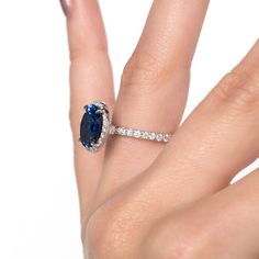 a woman's hand with a ring on it and an oval shaped blue sapphire