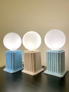 three lamps sitting on top of a table next to each other with different shapes and sizes