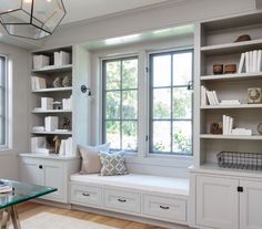 a window seat in the corner of a room with bookshelves and other items