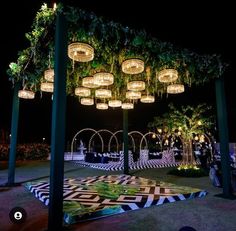 an outdoor wedding venue with lights and greenery on the ceiling, surrounded by black and white patterned rugs