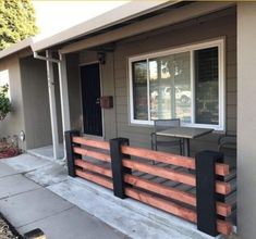 a small house with a table and chairs on the front porch, next to a fence