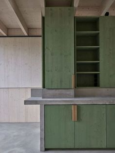 an empty kitchen with green cabinets and concrete counter tops