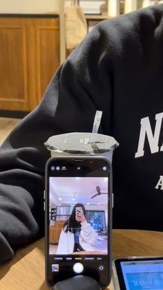 a cell phone sitting on top of a wooden table next to a cup with a straw in it