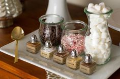 there are many different types of candies in glass jars on the tray next to each other